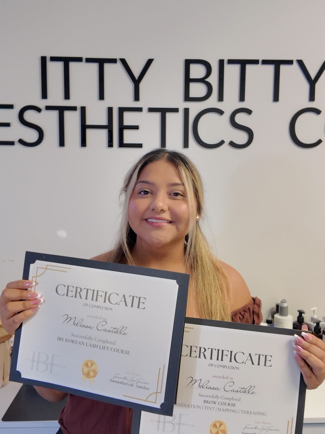 Graduate holding two Itty Bitty Esthetics certificates